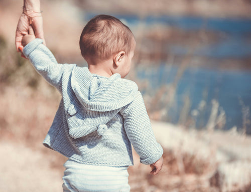 Little toddler holding parents hand wearing a cute gender neutral sweater. Discover sustainable, affordable, gently-loved children's clothing bundles at Bundled, supporting parents and the environment with curated, high-quality options for newborns to toddlers at affordable and cheap price points.