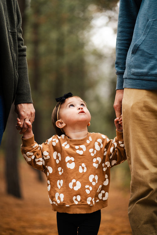 A family standing together holding hands wearing a cute outfit. Discover sustainable, affordable, gently-loved children's clothing bundles at Bundled, supporting parents and the environment with curated, high-quality options for newborns to toddlers at affordable and cheap price points.