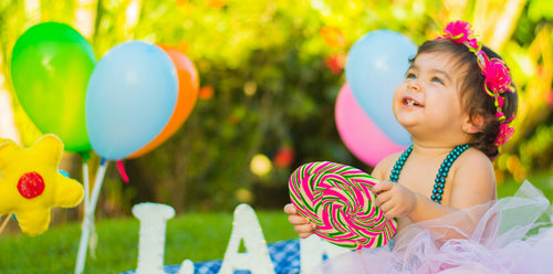 Little girl sitting outside with a big smile on celebrating a special occasion - her birthday. Discover sustainable, affordable, gently-loved children's clothing bundles at Bundled, supporting parents and the environment with curated, high-quality options for newborns to toddlers at affordable and cheap price points.