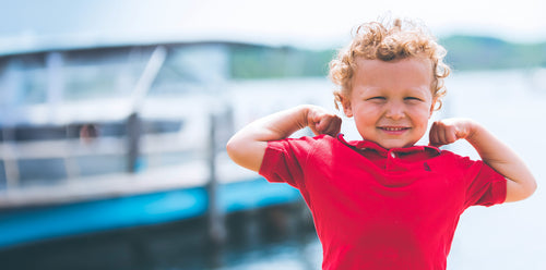 Little boy wearing a red shirt and smiling. Discover sustainable, affordable, gently-loved children's clothing bundles at Bundled, supporting parents and the environment with curated, high-quality options for newborns to toddlers at affordable and cheap price points.